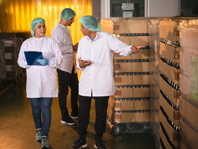 Two inspector scientists checking stock juice in glass bottle